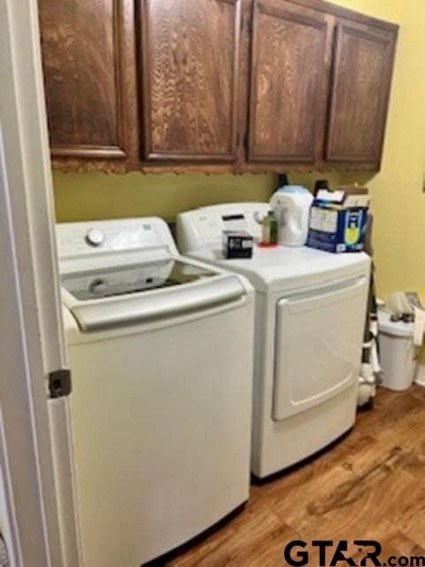 laundry room with cabinets, light wood-type flooring, and washing machine and dryer