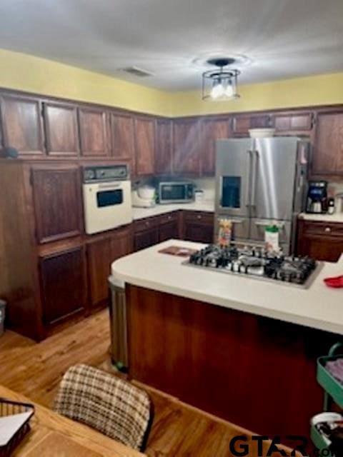 kitchen featuring dark brown cabinetry, appliances with stainless steel finishes, and light hardwood / wood-style flooring