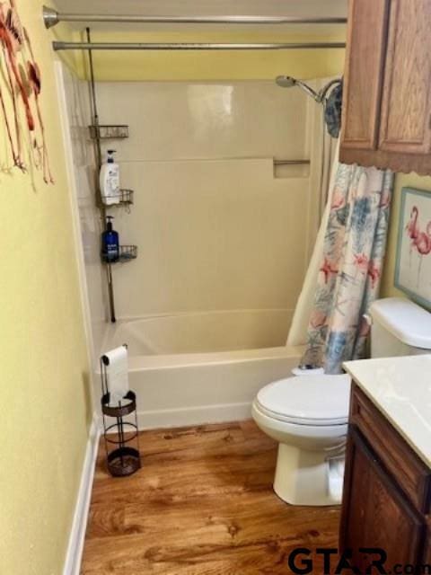 full bathroom with shower / bath combo with shower curtain, hardwood / wood-style floors, vanity, and toilet