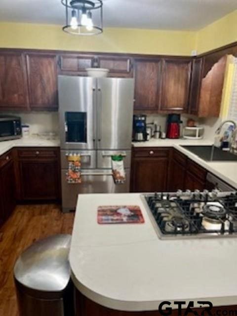 kitchen featuring dark brown cabinetry, sink, appliances with stainless steel finishes, and dark wood-type flooring