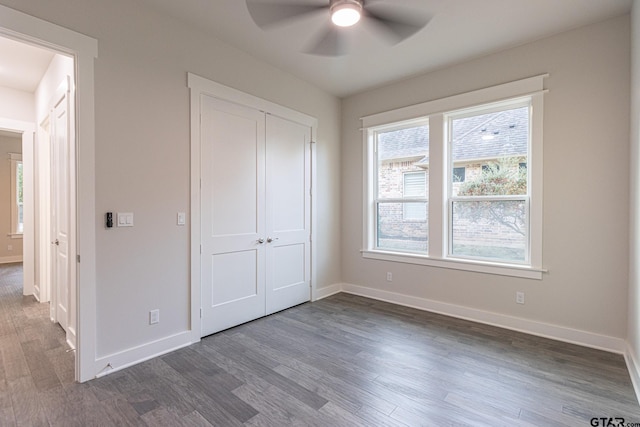 unfurnished bedroom featuring dark wood-type flooring, a closet, and ceiling fan