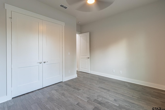 unfurnished bedroom with hardwood / wood-style flooring, ceiling fan, and a closet