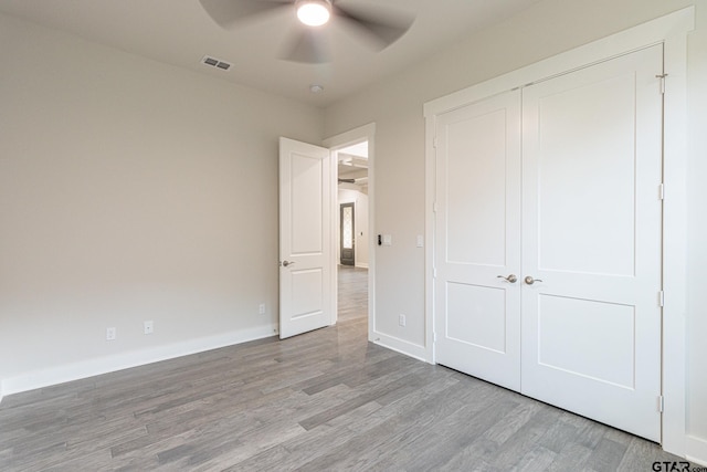 unfurnished bedroom featuring light wood-type flooring, ceiling fan, and a closet