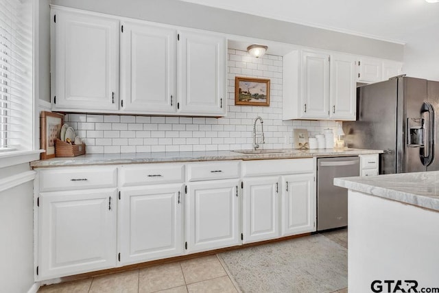 kitchen with sink, tasteful backsplash, light tile patterned floors, white cabinetry, and appliances with stainless steel finishes