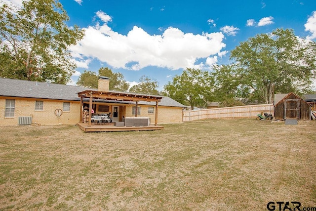 back of house with central AC, a lawn, a storage unit, and a deck