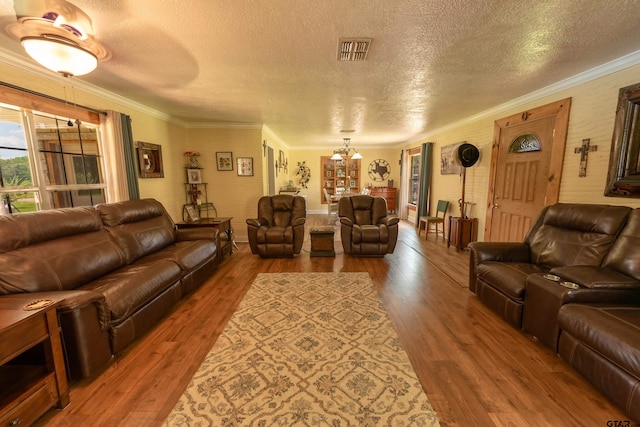 living room with a notable chandelier, a textured ceiling, hardwood / wood-style flooring, and crown molding