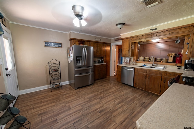 kitchen with appliances with stainless steel finishes, sink, crown molding, and dark hardwood / wood-style flooring