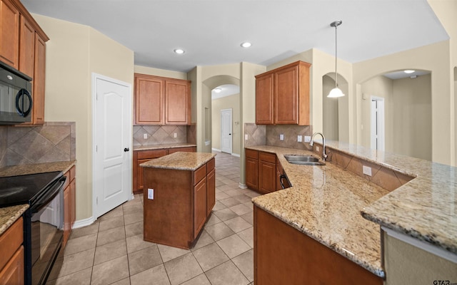 kitchen featuring pendant lighting, sink, a center island, black appliances, and light stone countertops