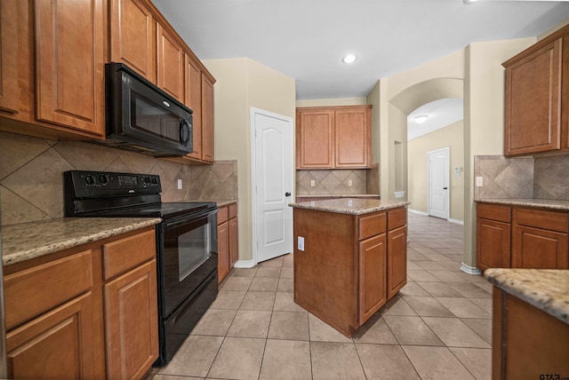 kitchen with light stone countertops, light tile patterned floors, decorative backsplash, and black appliances