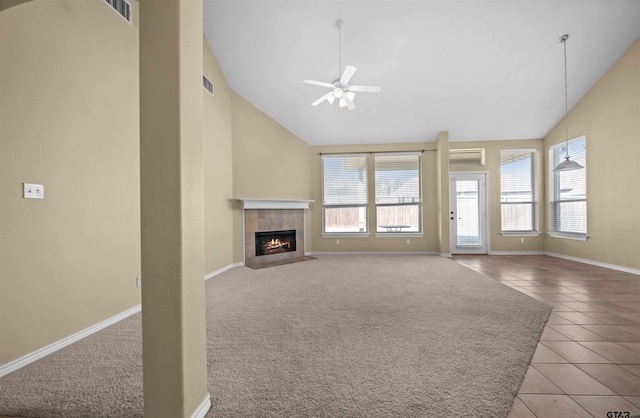 unfurnished living room with a tiled fireplace, ceiling fan, light tile patterned floors, and high vaulted ceiling