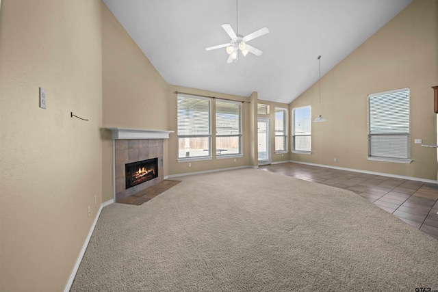 unfurnished living room featuring high vaulted ceiling, a tile fireplace, ceiling fan, and carpet