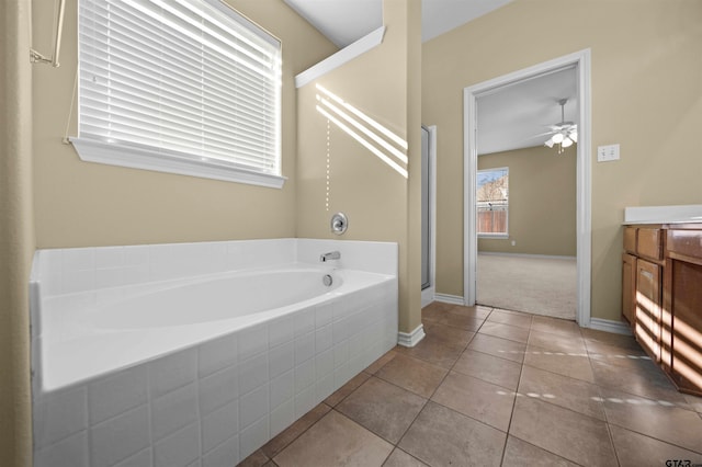 bathroom featuring tile patterned flooring, vanity, a relaxing tiled tub, and ceiling fan