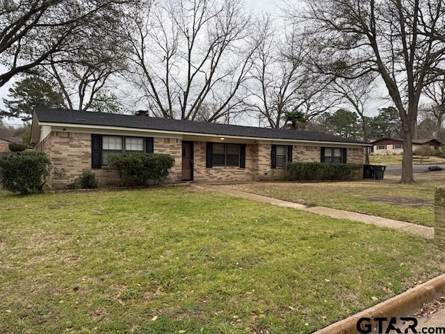 ranch-style home with brick siding, a chimney, and a front lawn