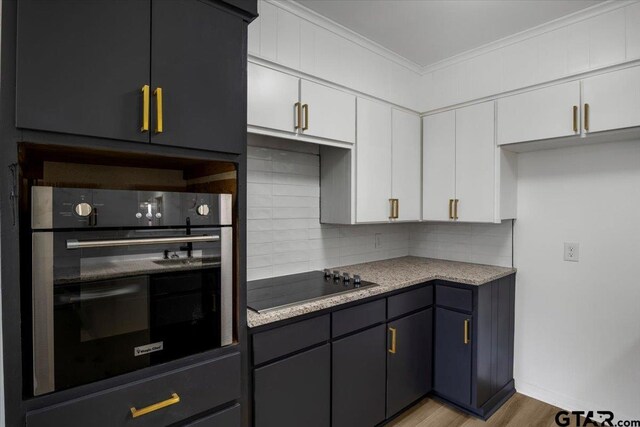kitchen with ornamental molding, wall oven, light wood-type flooring, black electric cooktop, and backsplash
