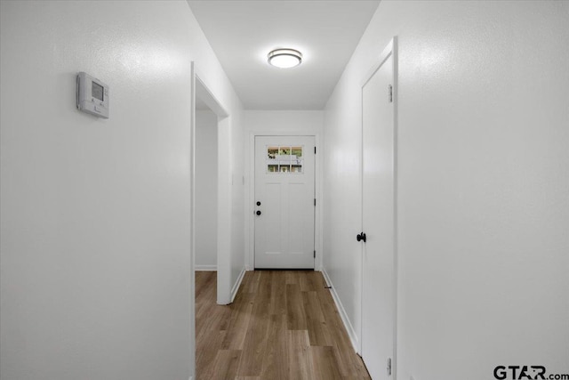 corridor with baseboards and wood finished floors