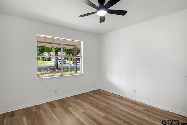 empty room with baseboards, a ceiling fan, and wood finished floors