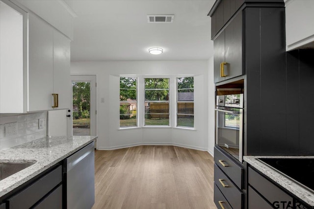 kitchen featuring backsplash, visible vents, appliances with stainless steel finishes, baseboards, and light wood finished floors