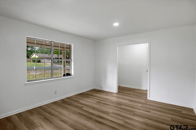 spare room featuring baseboards, recessed lighting, and wood finished floors