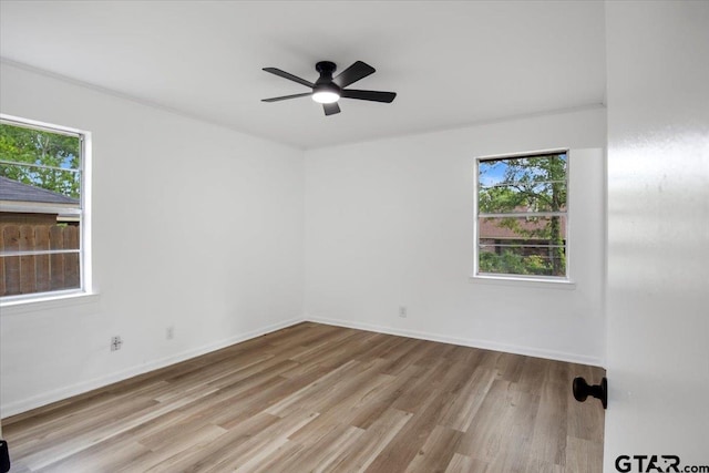 spare room featuring a ceiling fan, wood finished floors, and a healthy amount of sunlight