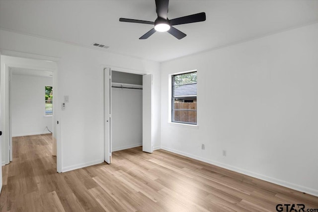 unfurnished bedroom featuring baseboards, visible vents, light wood finished floors, and a closet