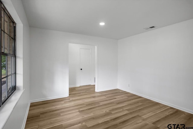 unfurnished room with visible vents, light wood finished floors, and baseboards