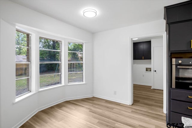 unfurnished dining area featuring baseboards, plenty of natural light, and light wood-style flooring