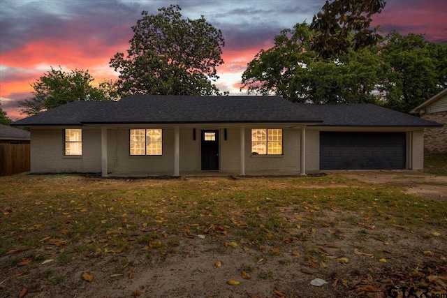 ranch-style home featuring a garage, fence, a front yard, brick siding, and a porch