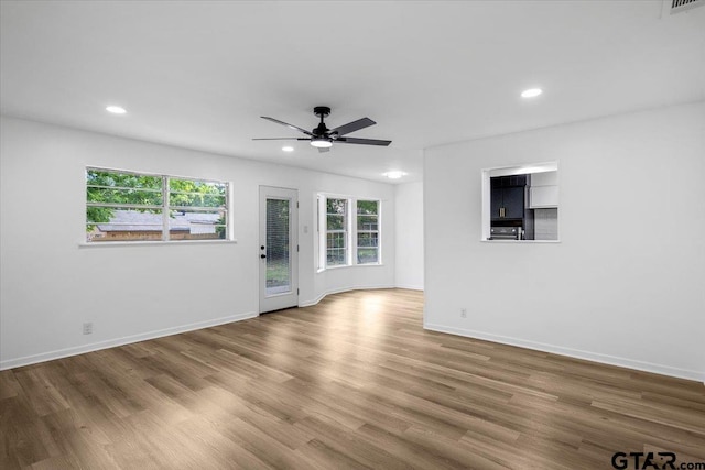 unfurnished living room with baseboards, a ceiling fan, recessed lighting, and wood finished floors