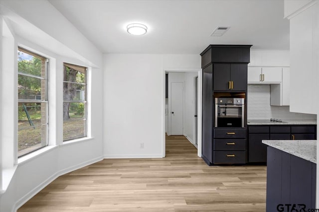 kitchen with stainless steel oven, white cabinetry, baseboards, light wood-type flooring, and visible vents