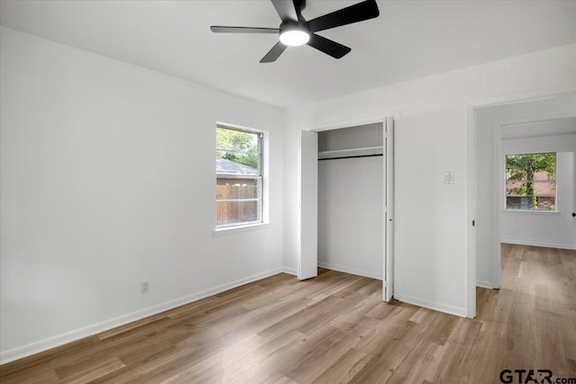 unfurnished bedroom with a closet, light wood-style flooring, ceiling fan, and baseboards