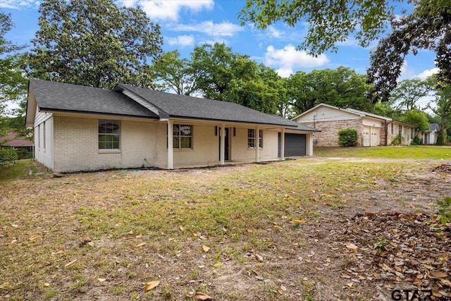 ranch-style home with a shingled roof, an attached garage, a front yard, and brick siding