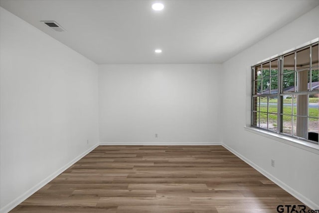 empty room with baseboards, recessed lighting, wood finished floors, and visible vents
