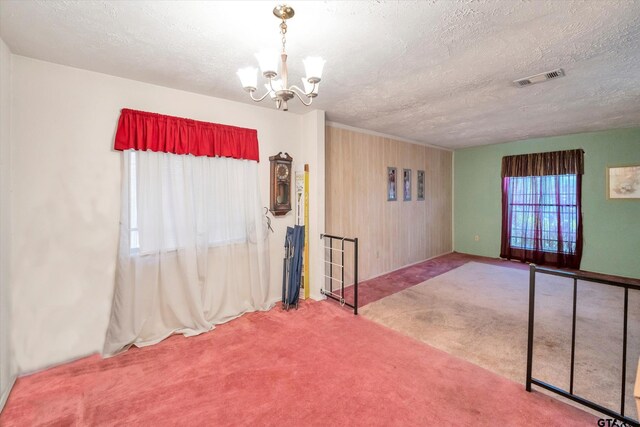12411 Drifting Winds Dr, Houston, TX 77044 - spare room with carpet flooring, a chandelier, a textured ceiling, baseboards, and wooden walls