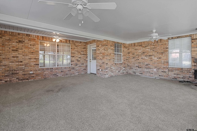 carpeted spare room with ceiling fan, brick wall, and a wood stove