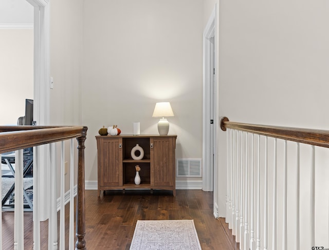 corridor with dark wood-type flooring and crown molding