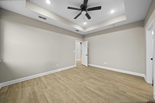 unfurnished bedroom with ceiling fan, a raised ceiling, and light hardwood / wood-style flooring