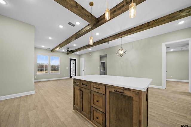 kitchen featuring light wood-type flooring, decorative light fixtures, beamed ceiling, ceiling fan, and a center island