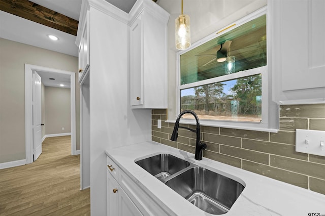 kitchen featuring white cabinetry, hanging light fixtures, decorative backsplash, light hardwood / wood-style floors, and beamed ceiling