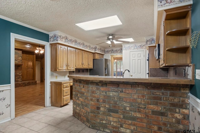 kitchen featuring ornamental molding, a textured ceiling, a skylight, stainless steel fridge with ice dispenser, and light wood-type flooring