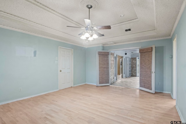 empty room with a textured ceiling, light hardwood / wood-style flooring, and ornamental molding