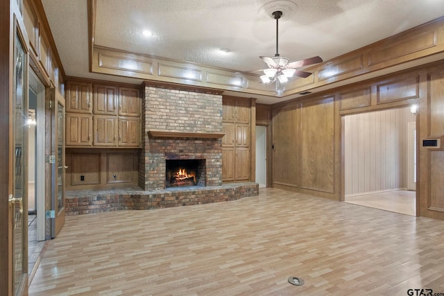 unfurnished living room featuring wood walls, a textured ceiling, and light wood-type flooring