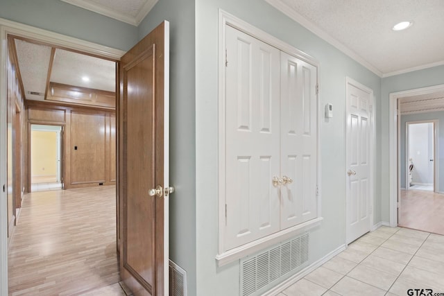 hall featuring light hardwood / wood-style floors, a textured ceiling, and ornamental molding