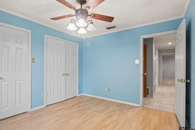 unfurnished bedroom featuring ceiling fan, a textured ceiling, light hardwood / wood-style flooring, and crown molding