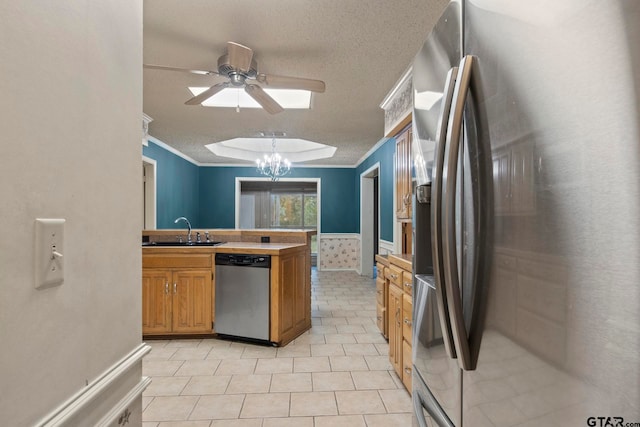 kitchen with stainless steel appliances, sink, ornamental molding, ceiling fan with notable chandelier, and a textured ceiling