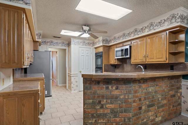 kitchen with kitchen peninsula, a textured ceiling, ceiling fan, crown molding, and appliances with stainless steel finishes