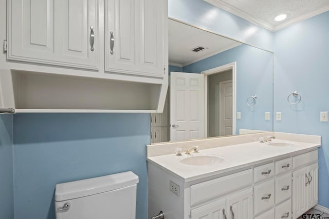 bathroom featuring toilet, vanity, a textured ceiling, and ornamental molding