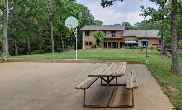 view of home's community featuring a lawn and basketball hoop