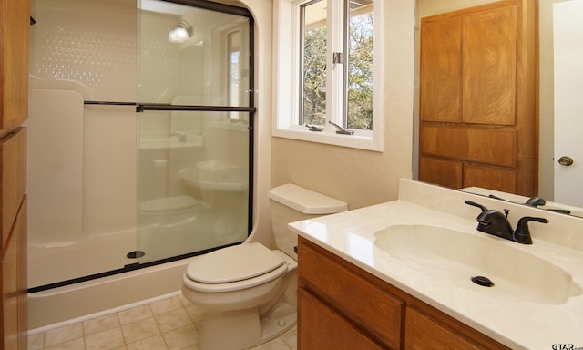 bathroom featuring tile patterned floors, vanity, toilet, and a shower with door