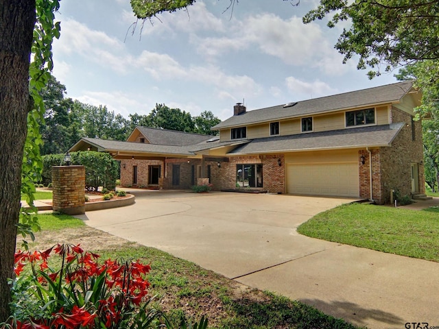 traditional home with driveway, a chimney, an attached garage, a front lawn, and brick siding