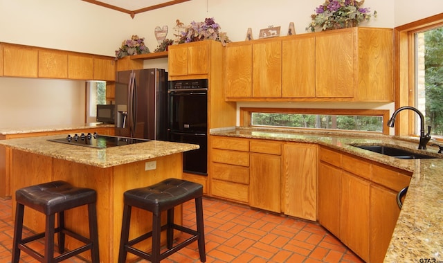 kitchen featuring a kitchen bar, sink, a kitchen island, and black appliances